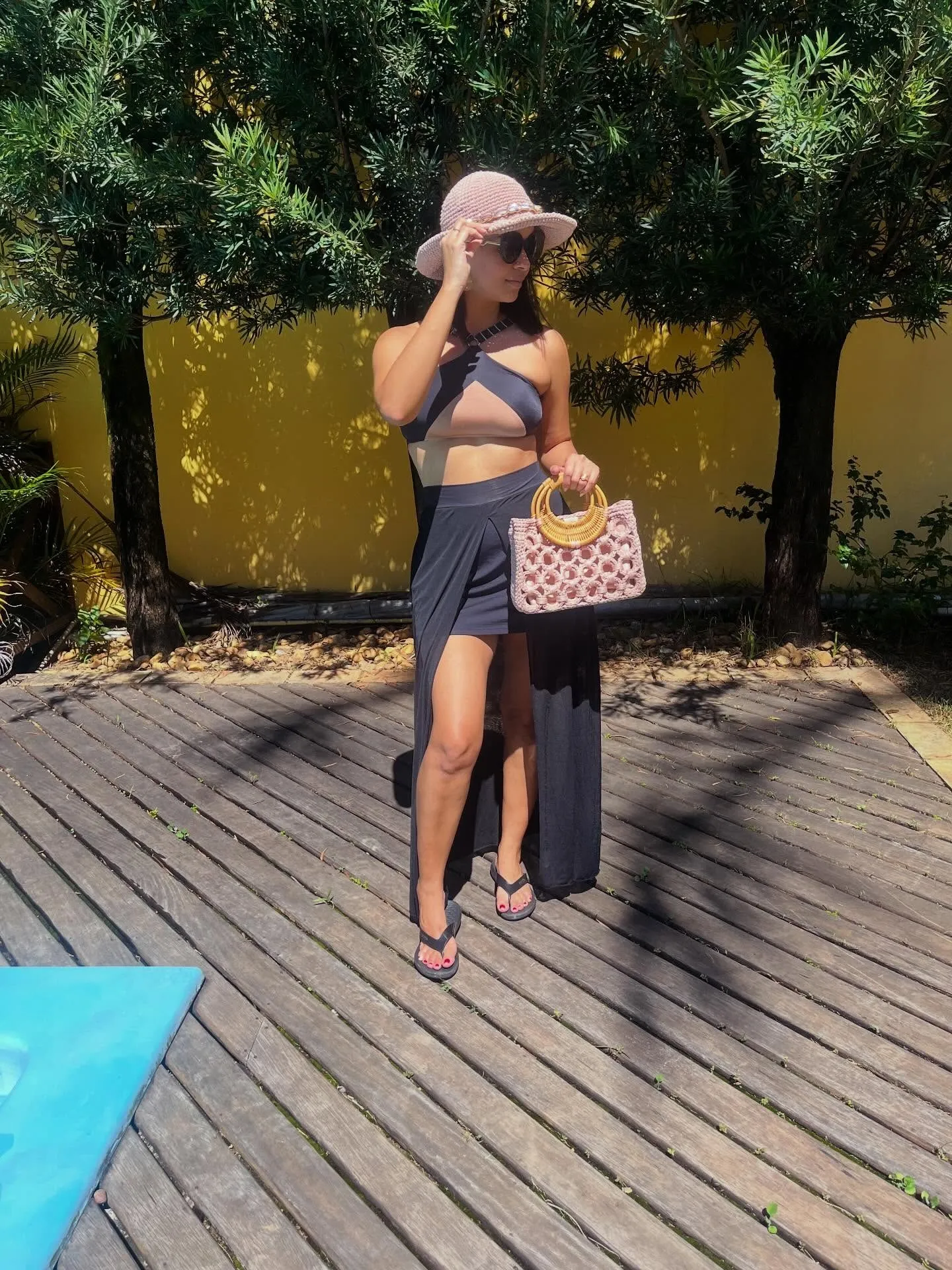 A Bolsa Grécia rosa em uso, num deque de madeira