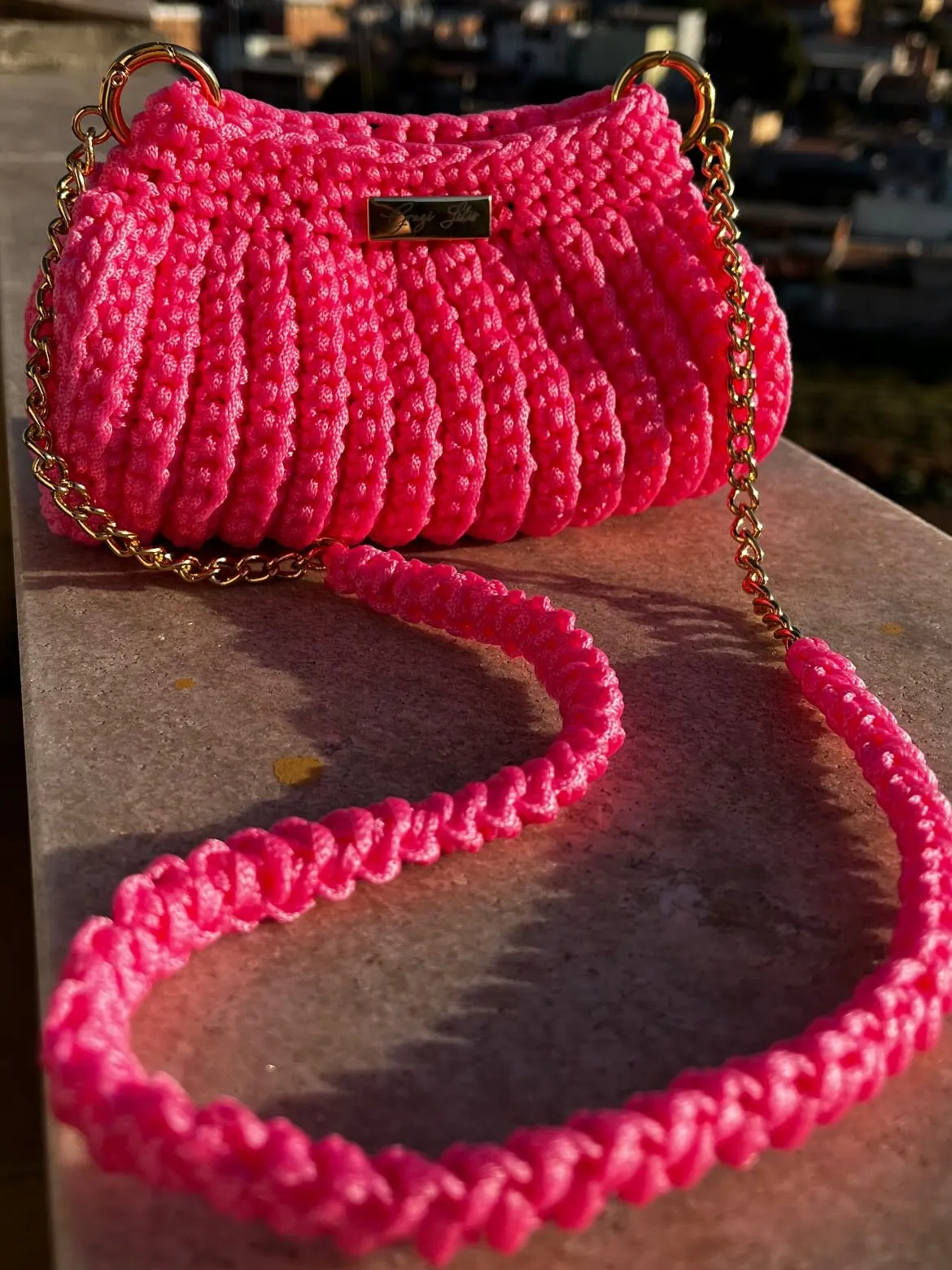 Pink crochet Julinha Bag with a gold chain and a long braided strap