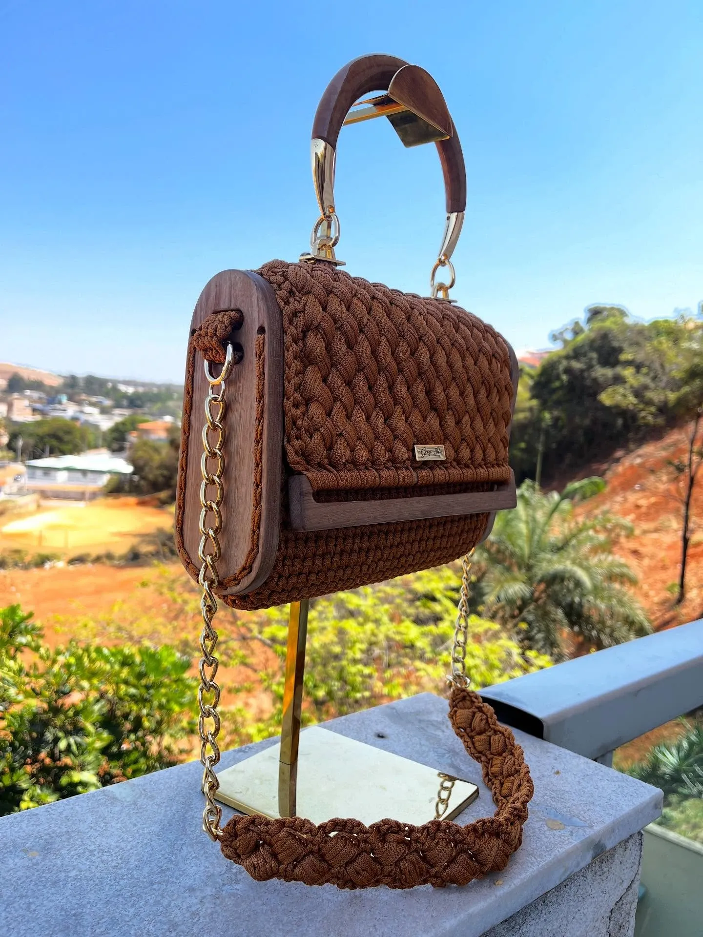 Bolsa Madeira caramelo em crochê, com laterais e alça de madeira, corrente dourada e alça trançada