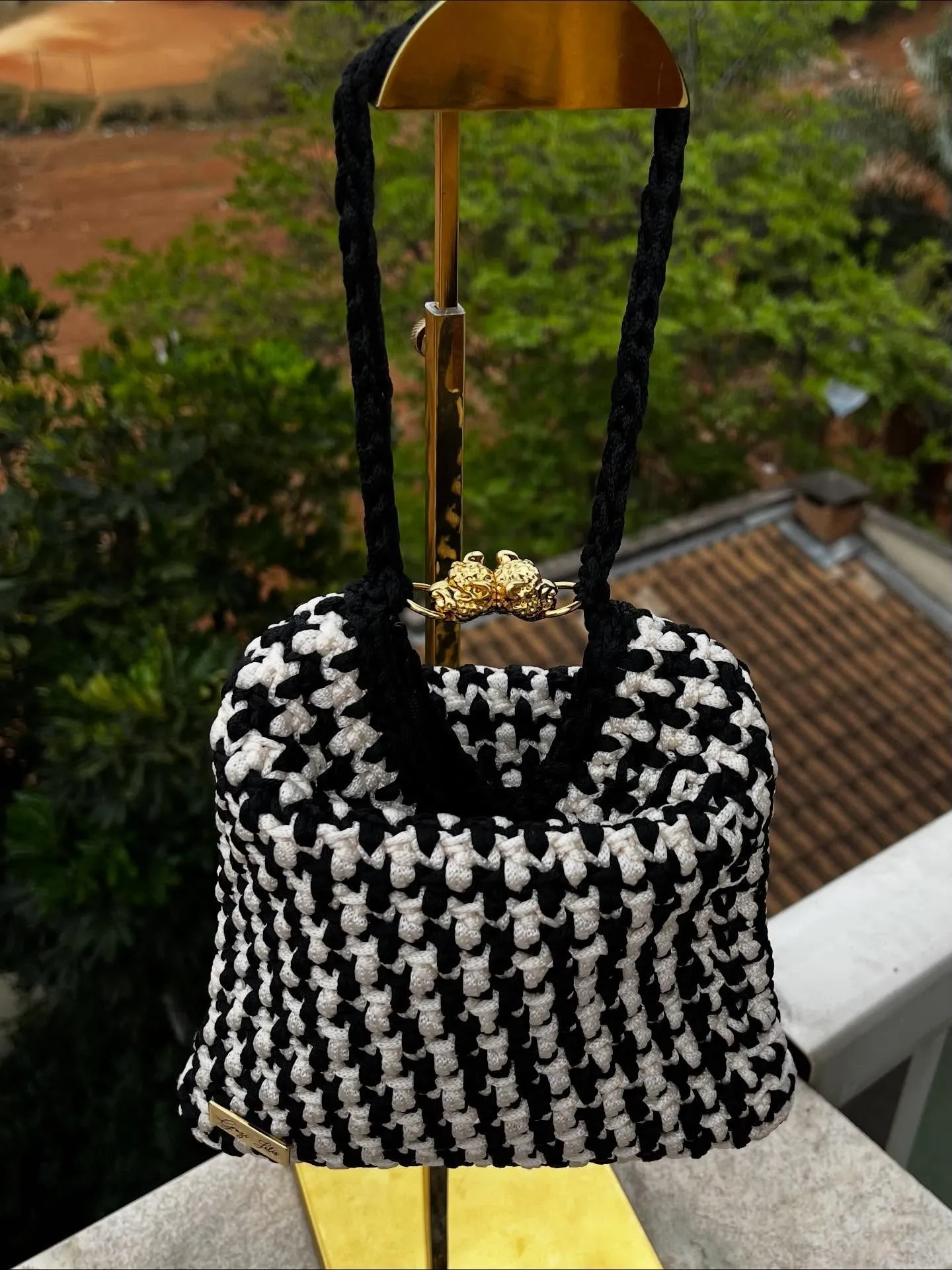 Bolsa Uau pendurada num suporte dourado, vista de frente