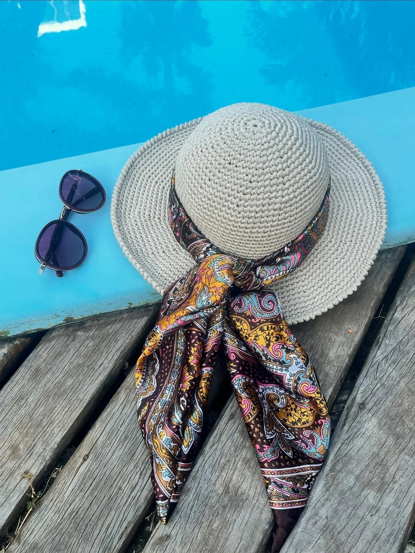Chapéu Malibu com lenço e óculos de sol na beira da piscina